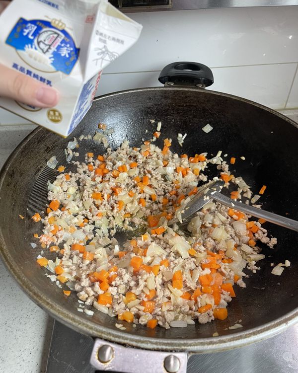 牛奶入味軟化
轉中小火倒入全脂牛奶，耐心慢熬直到牛奶被肉末完全吸收，這個步驟能鎖住肉汁並透過乳脂讓絞肉質地變得軟嫩如絲、入口即化。