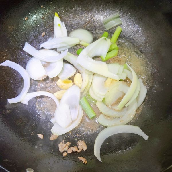 用鍋中炒牛肉的油水，爆香蔥白、蒜頭和洋蔥，炒至洋蔥軟化透明