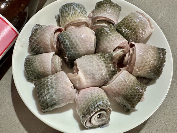 ●台灣產的冷凍真空包虱目魚皮，烹煮前一餐放冷藏低溫解凍，剪開真空包後沖洗過去血水瀝乾，平放在上盤子上捲成魚卷，放在有能入電鍋的瓷盤裡，魚皮有滿滿的膠質，蒸熟後會黏住盤子，魚卷擺放可想一下希望的呈現。