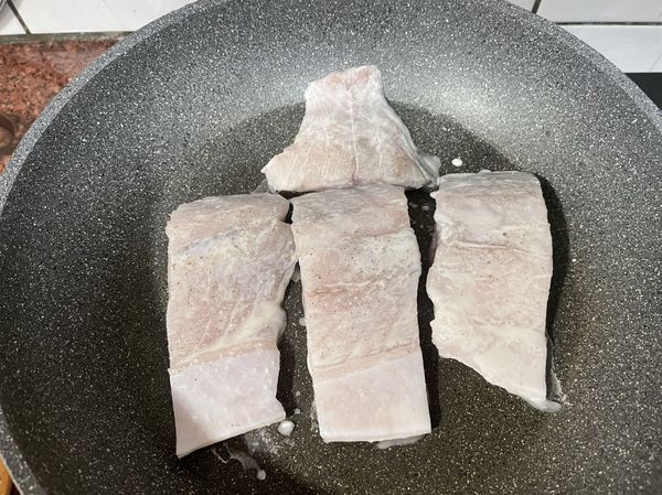 過中加入一大匙油，將鱸魚片雙面沾上粉漿，皮朝下放入鍋中，蓋上鍋蓋，中小火慢煎，煎至魚片邊緣金黃酥脆