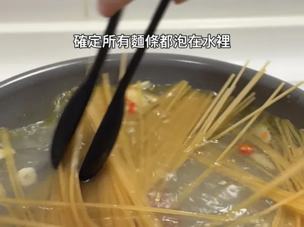 麵條稍微軟化後，用夾子輕輕攪拌麵條，確定所有麵條都泡在水裡。因為煮麵的水分較少，所以要比包裝指示的時間再多煮1~2分鐘。