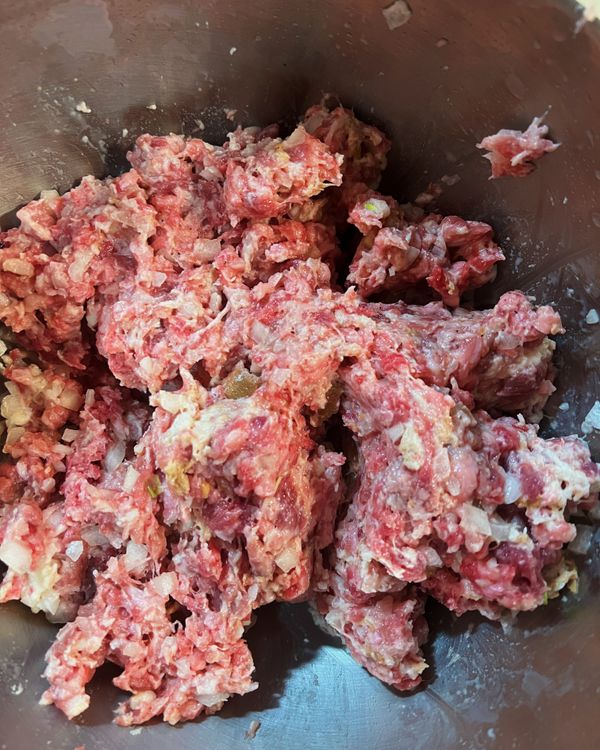 麵包粉加入牛奶浸泡一下。
將牛絞肉、豬絞肉、洋蔥丁與浸泡牛奶的麵包粉拌勻。