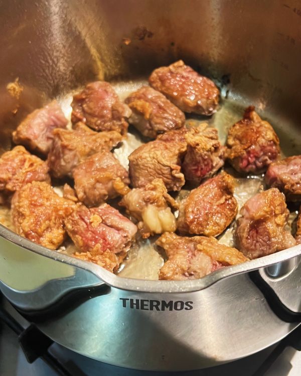 先將牛肉表面均勻沾上中筋麵粉。
鍋中加入橄欖油，以中大火將牛肉塊表面煎至金黃取出備用。