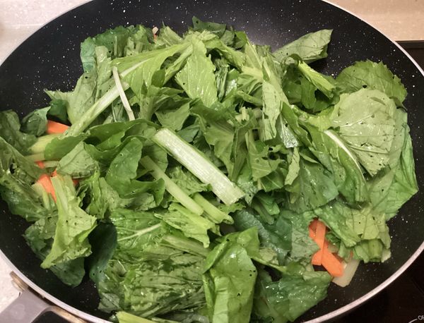加入黑葉白菜的葉子一起拌炒，加入鹽巴跟水炒軟