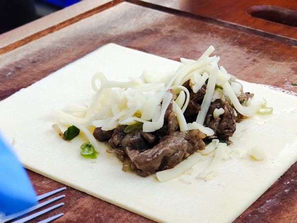 起酥皮攤開，鋪上餡料、乳酪絲。