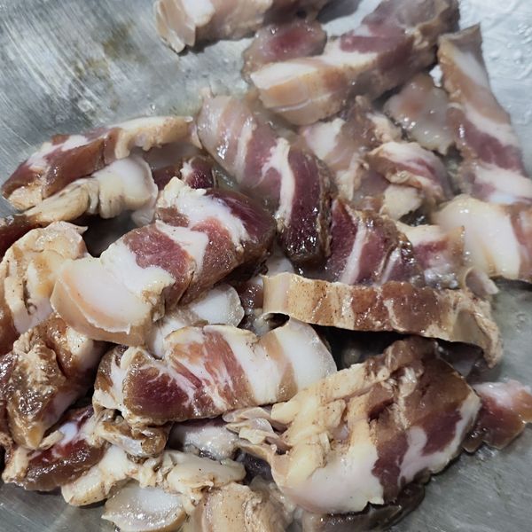 加熱鍋具，倒入食用油，臘肉洗淨後切薄片放入鍋中拌炒。（因為臘肉是恩典製，所以切片直接如果炒，如果是市售的臘肉，建議沖過熱水後再炒。