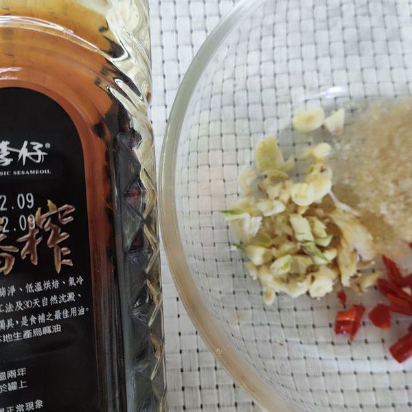 趁芒果殺青動作的時間，我們來調醬汁。將蒜頭去膜切成蒜末；紅辣椒洗淨切斜紋刀，將蒜末、辣椒丁、砂糖、麻油放入料理碗裡。