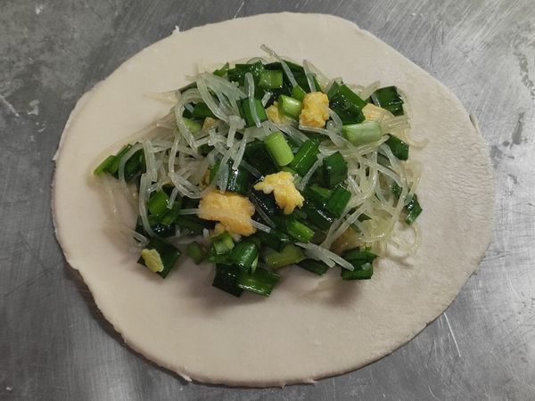 將內餡置於麵皮中間，在於麵皮周圍半圓形處塗抹少許水