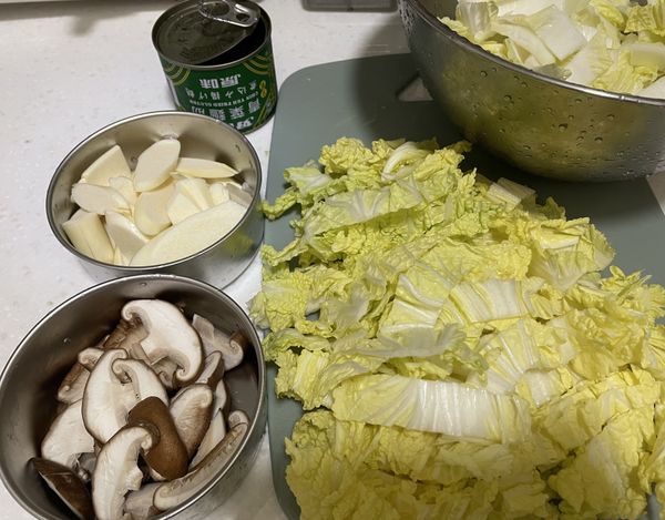 食材洗淨後，將大白菜切長條（菜梗跟菜葉分開）、香菇切條、茭白筍切片備用。
