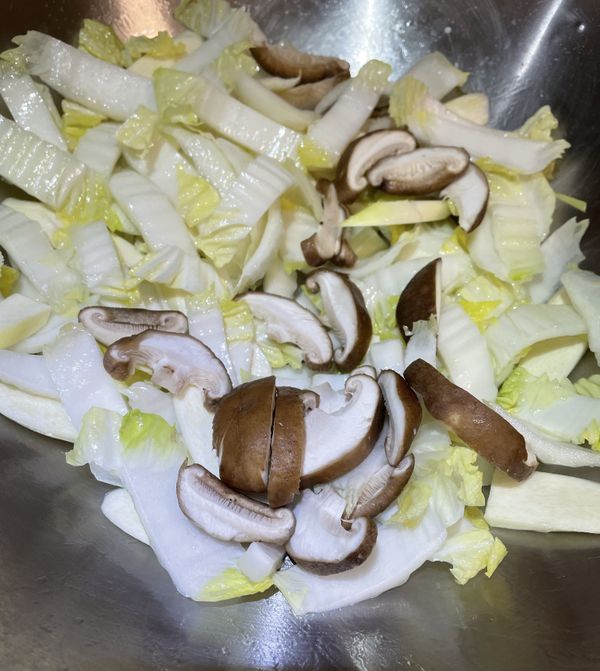 熱鍋，放入一大匙玄米油，加入大白菜菜梗、茭白筍和香菇拌炒，炒至蔬菜稍微變軟。