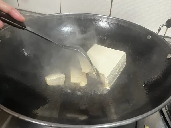 整塊豆腐下油鍋去煎，並用煎鏟隨意切塊