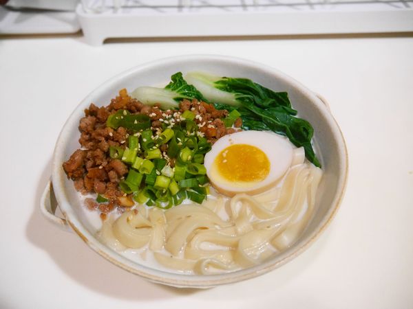 碗公中倒入煮好的濃湯底，依序加入寬版大麵、肉燥、蔬菜、蛋..等配料