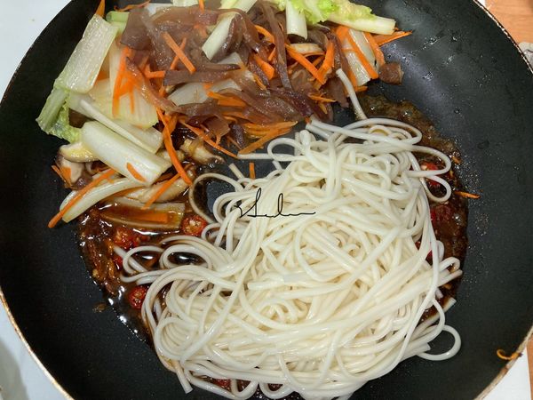 用手直接抓，把剛剛泡冰水的麵條放入醬中（不用瀝乾因為在炒的過程中需要水份)，中火，一手拿筷子一手拿大湯匙或是鍋鏟用拌的方式，將醬汁平均上色/融入麵條中。