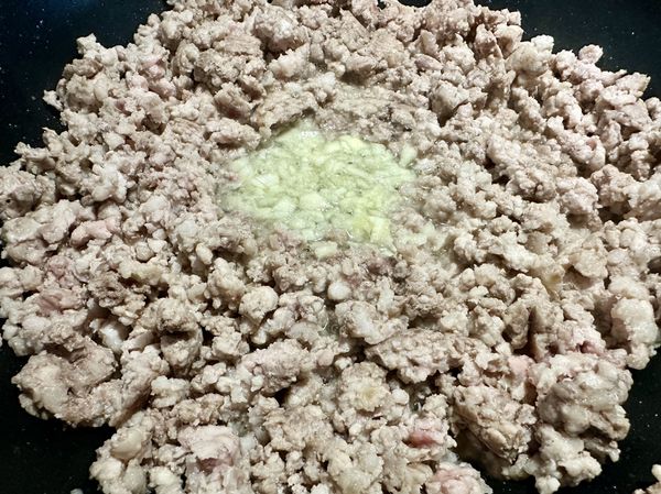 ●6分鐘到打開鍋蓋翻炒一下絞肉，炒到絞肉粒粒分明，油脂也收略收乾，這樣豬肉香氣才會出現，開始幫絞肉提香，用煸香豬絞肉冒出的油放(蒜末)拌炒煸出蒜香。