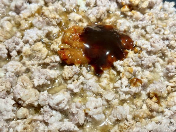 ●聞到蒜香開始做麻婆醬汁，豆瓣醬要煸炒過才會香，用乾淨湯匙挖(辣豆瓣醬、蠔油、白胡椒粉）用炒匙拌炒讓肉末均勻沾滿醬料再加(米酒、水)翻炒均勻，絞肉跟醬汁燒滾融合才會香。
