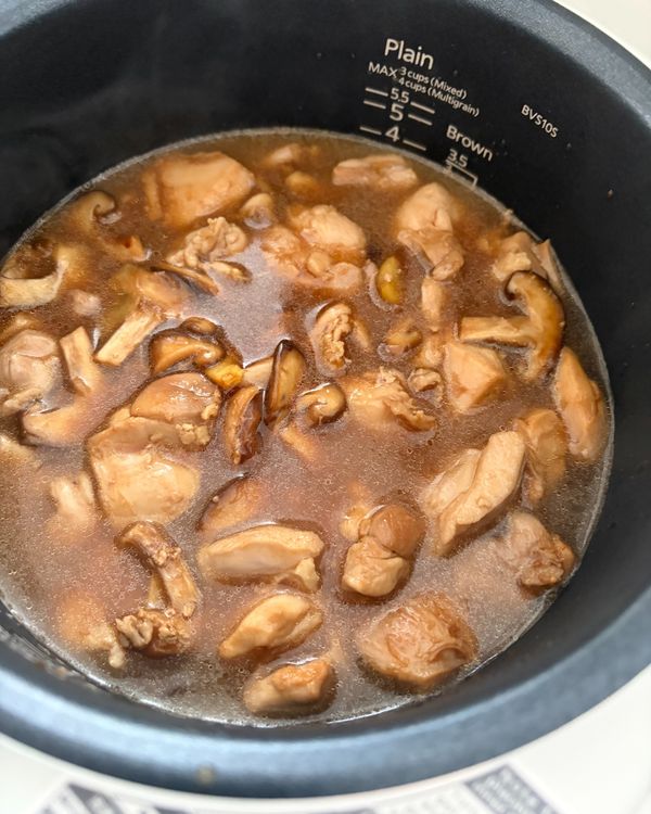 米飯入電鍋炊煮: 
白米洗淨後放入電鍋內鍋，加飲用水至刻度 2 的位置，水量比平常稍少約一湯匙（炒好的雞肉帶有汁水，飯粒才不會過軟）。將炒好的雞肉、香菇、薑片連同鍋底醬汁全部鋪在米上，按照「煮白米」功能啟動。