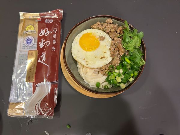 將麵撈起來，放入準備好的煎蛋、青蔥、香菜及剝皮辣椒皮蛋醬即完成。
