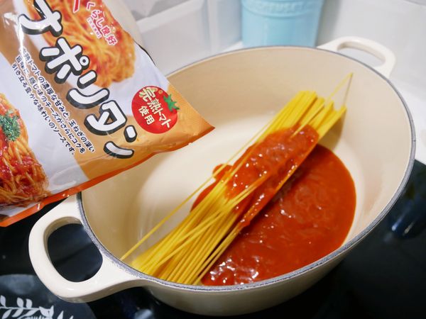 鍋中倒入些許橄欖油、放入義大利麵條並倒入義大利麵紅醬。