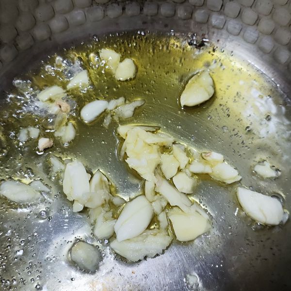 加熱鍋具，倒入食用油，蒜頭切成蒜末放入鍋中爆香加入。
