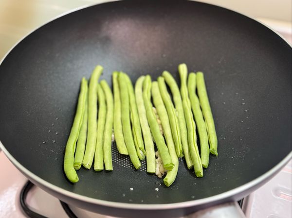 平底鍋加入少許橄欖油與部分蒜末。
放入四季豆與少許鹽巴。
煎至兩面微微上色，且仍保有脆度後取出備用。