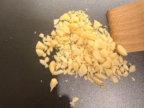 先將夏威夷豆用刀切成粗粗的碎粒，保留一點顆粒感咬起來更過癮。接著放進乾淨的平底鍋或電烤盤中，不用倒油，用中小火乾炒大約2分鐘，直到聞到濃濃的堅果奶香、表面有點金黃色，就可以撈起來放涼備用。