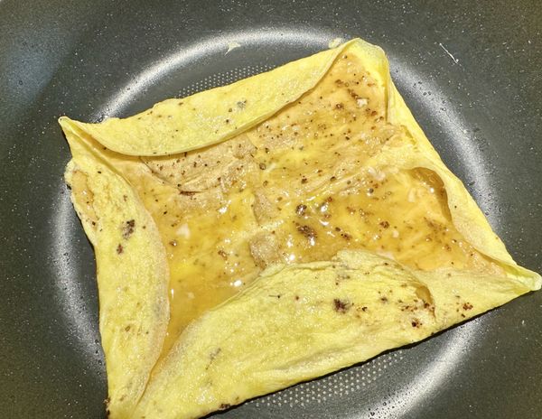 蛋液凝固時，用炒匙將蛋皮往豆包方向內褶。