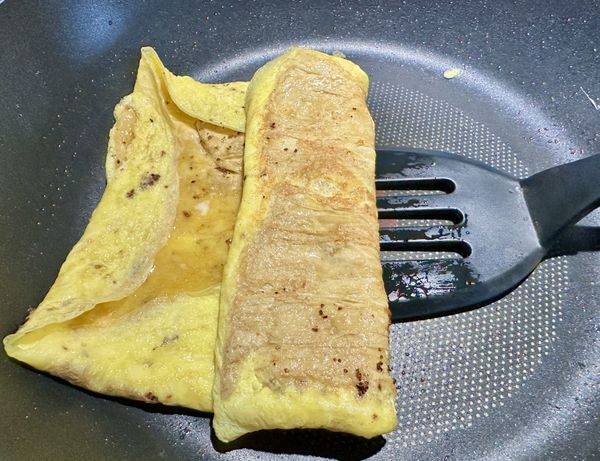 再用炒匙將豆皮蛋皮翻摺一摺，如照片。
