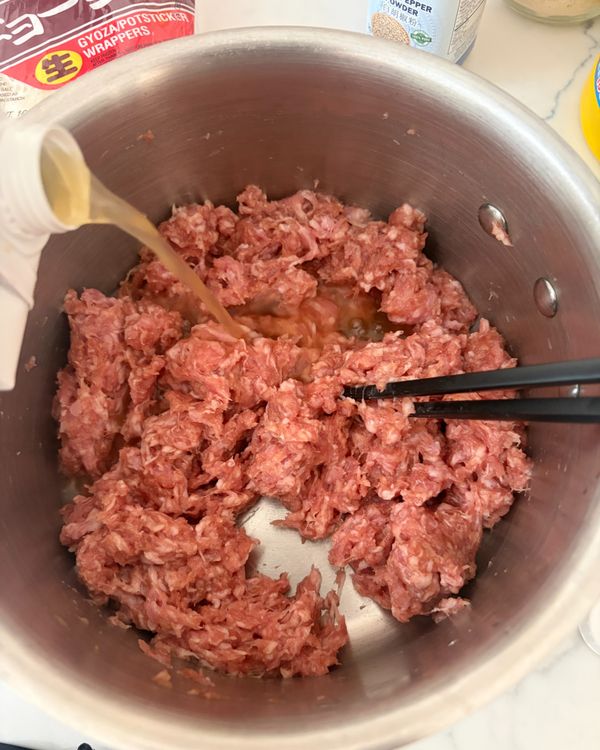 加入高湯　
少量分次加入高湯，每次加一點後攪拌均勻再視情況繼續加。肉餡狀態應為黏稠不流動——太濕會不好包，這步一定要控制好。
