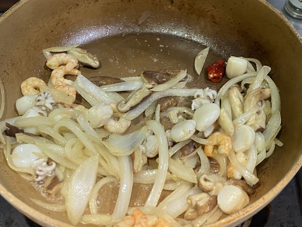 再加入洋蔥，炒到軟化，加入海鮮。