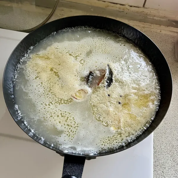 雞高湯或水中，加入薑片、月桂葉、陳片、米酒煮滾後，轉小火滾2分鐘。這是我自己用來增加去腥的方式，也可以什麼都不放，或放你自己覺得想加的香料如花椒粒、肉桂片、八角、蒜、蔥等。同時半雞的雞腳我也在這時一起放進去。