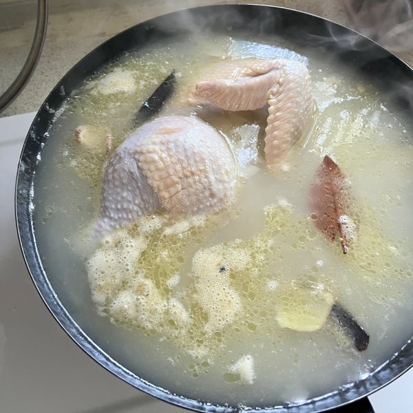 關火，將半雞浸泡在高湯或水中，泡20分鐘。我的鍋子不夠深，所以我有再用鍋蓋蓋上，最好是要讓所有雞肉泡在水中。我拍完照片後就把雞肉翻過來了，這樣接觸的部份會多得多。