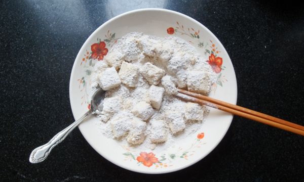 搗碎粗地瓜粉中過粗的顆粒，將澱粉均勻裹在切好的嫩豆腐上；