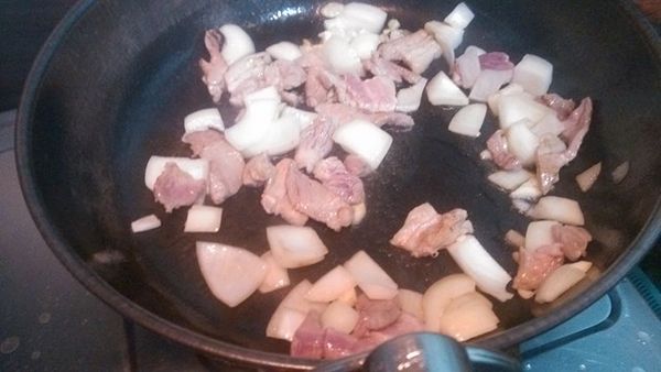 熱油鍋放少許食用油，開大火放入洋蔥、蒜片與肉丁炒約30秒。