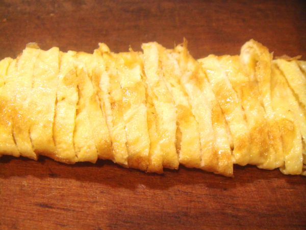 把雞蛋打散後，放入少許扣肉煸油，鍋熱後，倒入蛋液，將鍋內蛋液輕輕搖勻，煎成極薄蛋餅皮，煎熟後捲起，切成細絲放入砂鍋內