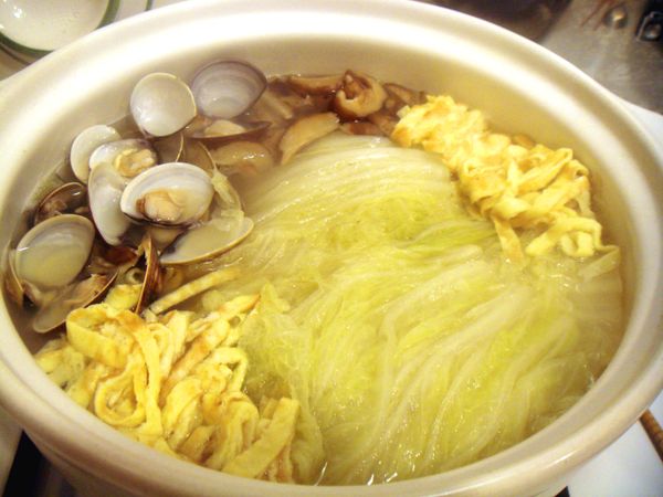 鍋內的白菜已經熟成，放入香菇絲、蛋絲及蛤蜊並蓋上鍋蓋燉煮至蛤蜊全開為止。