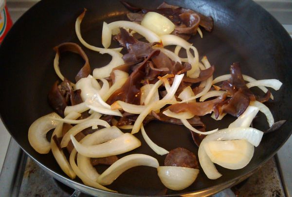 洋蔥切絲炒香，依序放入木耳及高麗菜拌炒，裝盤鋪底。