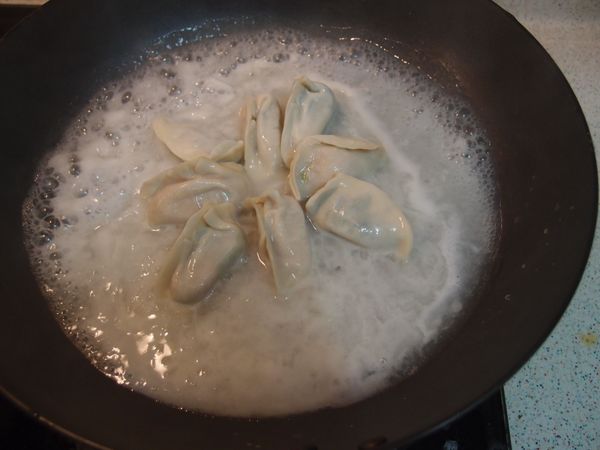 熱鍋後，平底煎鍋中抹少許油，
將水餃排在鍋中，倒入[麵粉水]。