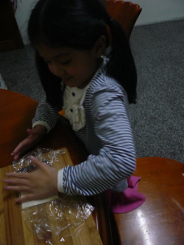 將去邊的土司以保鮮膜包好，讓小朋友用手壓實，這樣才能利用土司做出杯子形。自已動手做，對孩子而言是最幸福的事，如果你陪孩子試過，就會了解個中奧祕。