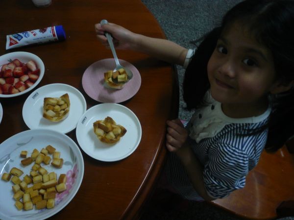 將取出的土司杯放盤子裡，用湯匙勺起土司丁放到土司杯底部。