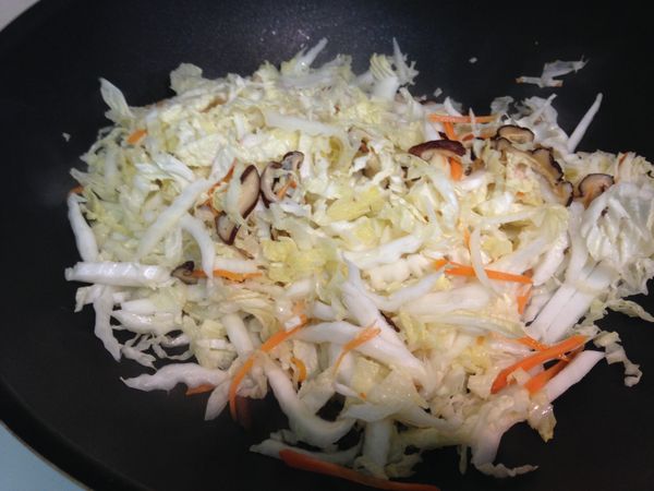 適量油熱鍋，香菇、紅蘿蔔絲、大白菜絲依序下鍋炒香。