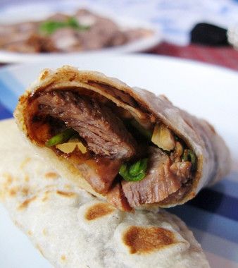 取一張餅皮擦上適量甜麵醬，放上蔥段、小黃瓜絲(不加也可)和牛肉薄片捲起即可