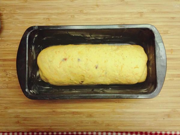 將長方形麵糰翻面，由短邊處捲起成圓柱狀，收口朝下，放入抹了奶油的烤模內進行第二次發酵。