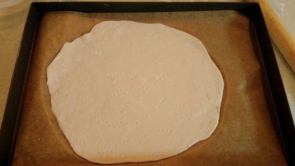 取6片餃皮捏成團後，靜置約10分鐘，再拿桿麵右手桿，左手輕輕向外將餃皮拉大拉薄。

用叉子在餅皮上戳些氣孔，等等烤的時候才不會膨脹。