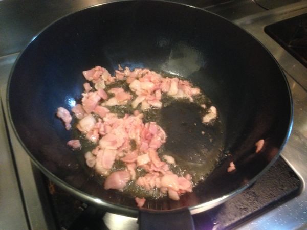 取炒鍋倒入香油爆炒培根碎及洋蔥。