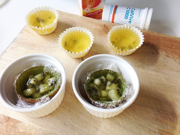 再將步驟6的諾鈣C果凍液填滿。(也可以直接用紙模操作如後)。放進冰箱冷藏約4~5個小時凝固後，再把保鮮膜拿掉就可以享用嚕~