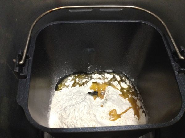 將A材料的中筋粉、全麥粉、泡打粉過篩後倒入麵包機容器，鹽和苦茶油也加進去。