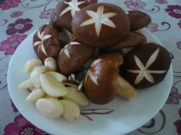 將香菇洗淨，以刀子在菇面刻米字形；蒜頭去膜備用。