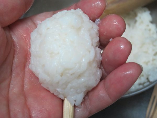 兩手冷開水沾溼，取適量米糰插入棒子。再往下推出長型米糰。