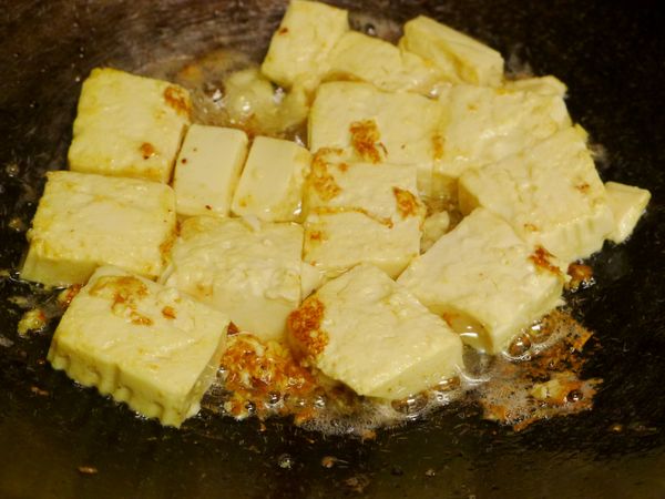 將切成塊狀的豆腐倒入鍋中，用鍋內洋蔥爆香過的油以中大火將豆腐香煎至兩面金黃