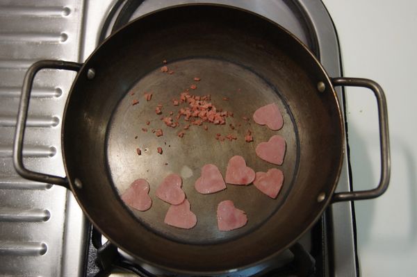 取一平底鍋，加入少許的油，放入裁完的愛心火腿，與火腿細末將它香煎過後即可